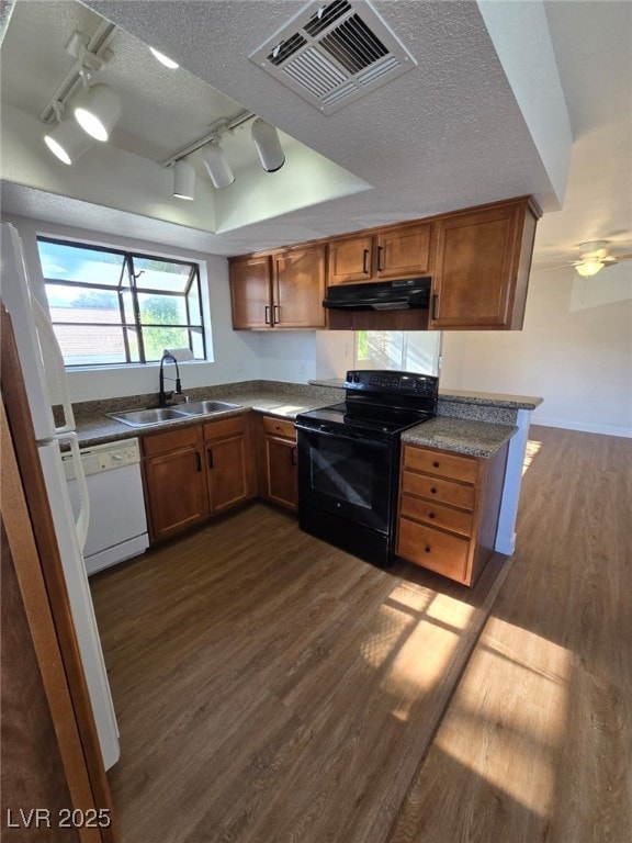 kitchen featuring a sink, white appliances, rail lighting, dark wood-type flooring, and under cabinet range hood