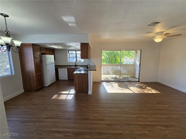 kitchen featuring visible vents, dark countertops, white appliances, dark wood-type flooring, and a sink