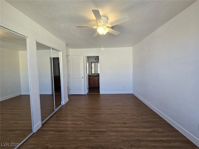 interior space with baseboards, two closets, dark wood-style floors, and a textured ceiling
