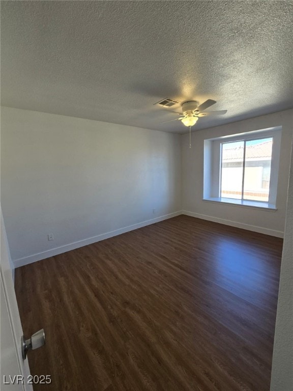 unfurnished room featuring baseboards, a textured ceiling, and dark wood finished floors