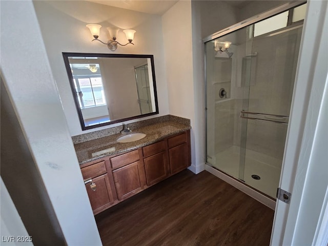 bathroom featuring an inviting chandelier, vanity, a stall shower, and wood finished floors