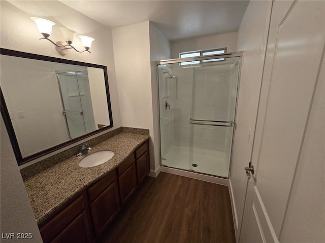 full bathroom featuring vanity, baseboards, a stall shower, and wood finished floors