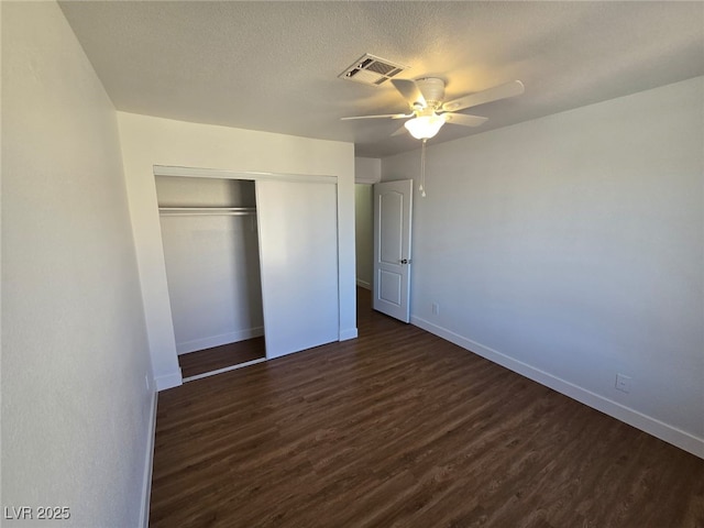 unfurnished bedroom with baseboards, a closet, dark wood-style floors, and visible vents