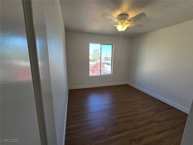 spare room with a ceiling fan, baseboards, dark wood-style floors, and a textured ceiling