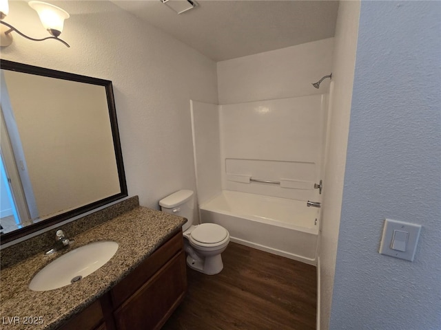 bathroom with visible vents, vanity, wood finished floors, toilet, and  shower combination