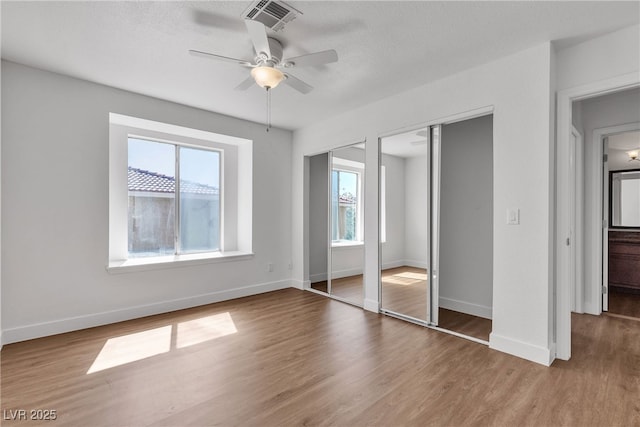 7200 Pirates Cove Rd Unit 2025, Las Vegas, NV 89145 - unfurnished bedroom featuring multiple windows, two closets, wood finished floors, and baseboards