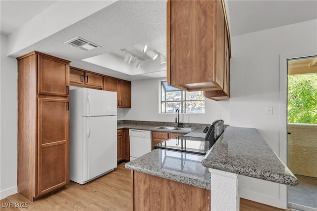 7200 Pirates Cove Rd Unit 2025, Las Vegas, NV 89145 - kitchen with white appliances, a sink, a peninsula, light wood-style flooring, and brown cabinets