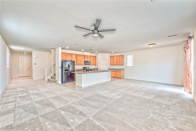 156 Fulgora St, Henderson, NV 89074 - kitchen with visible vents, black refrigerator with ice dispenser, open floor plan, light colored carpet, and stainless steel microwave