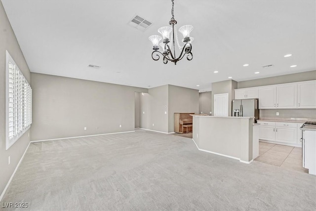 2525 Willow Wren Dr, North Las Vegas, NV 89084 - kitchen with stainless steel fridge, light colored carpet, a chandelier, baseboards, and white cabinets