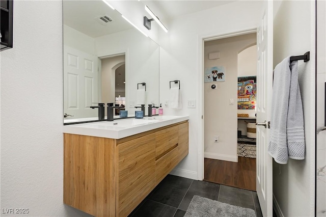 full bath featuring double vanity, visible vents, a sink, tile patterned floors, and baseboards