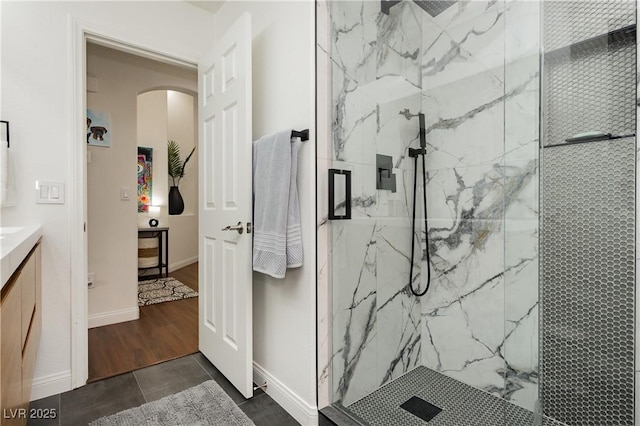 bathroom featuring a marble finish shower, baseboards, and vanity
