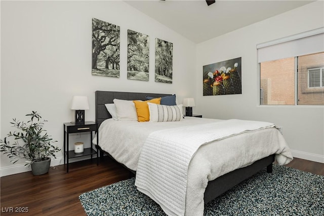 bedroom featuring baseboards, wood finished floors, and lofted ceiling