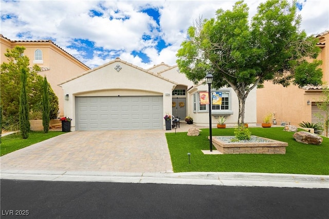 mediterranean / spanish-style house featuring stucco siding, decorative driveway, and a front yard