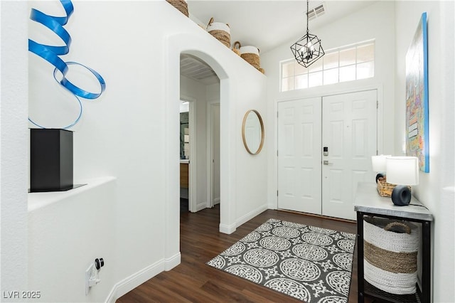 entrance foyer featuring arched walkways, baseboards, visible vents, and dark wood-type flooring