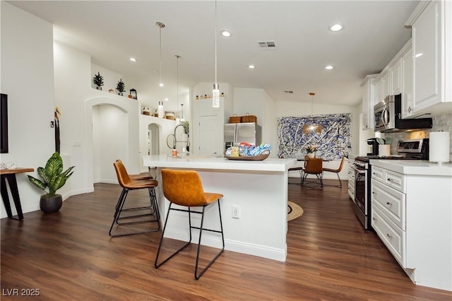 kitchen featuring a kitchen bar, visible vents, dark wood finished floors, light countertops, and stainless steel appliances