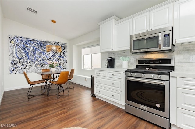 kitchen with dark wood-style floors, light countertops, white cabinetry, backsplash, and stainless steel appliances