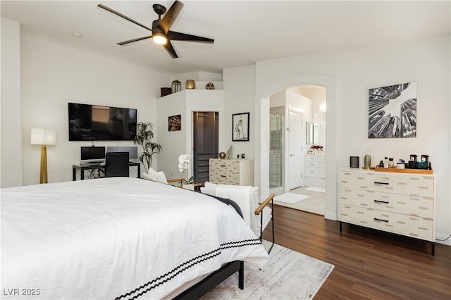 bedroom featuring arched walkways, a ceiling fan, ensuite bathroom, and dark wood-type flooring