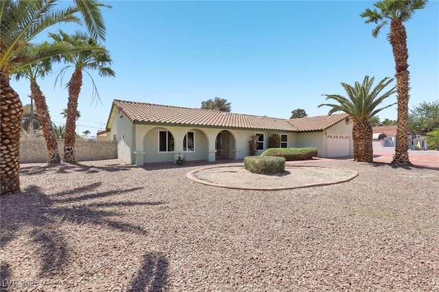 mediterranean / spanish-style home featuring an attached garage, stucco siding, driveway, and fence