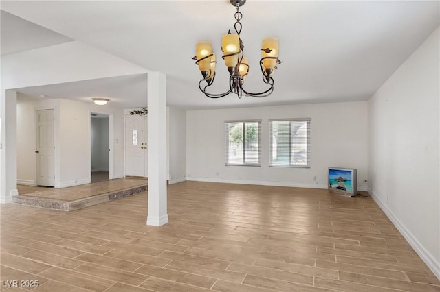 unfurnished living room with light wood-type flooring, baseboards, and a chandelier