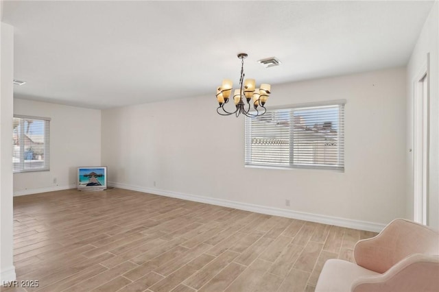 interior space featuring an inviting chandelier, baseboards, light wood finished floors, and visible vents