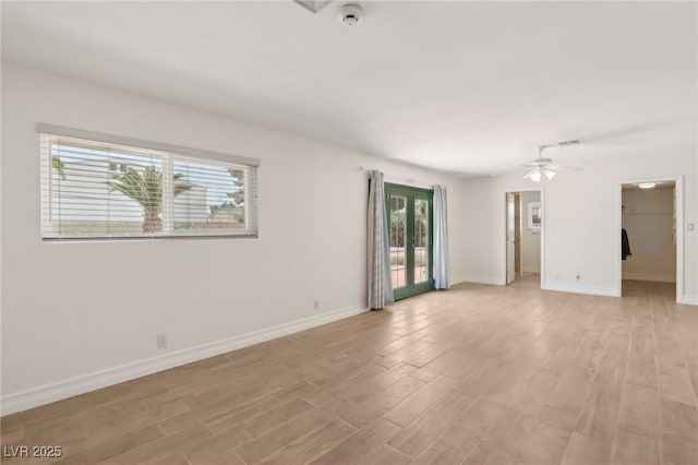 spare room with baseboards, ceiling fan, and light wood-style flooring