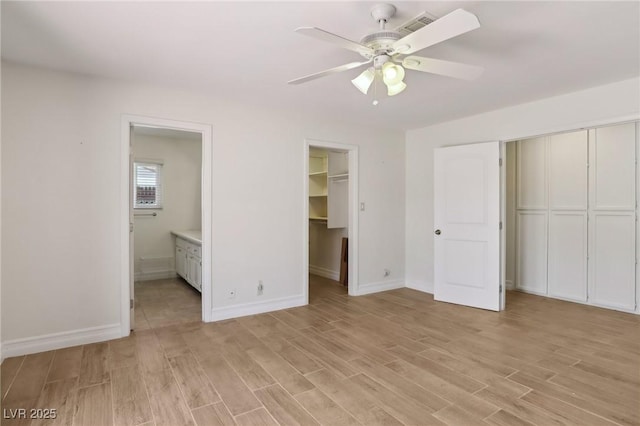 unfurnished bedroom featuring baseboards, a ceiling fan, light wood finished floors, and ensuite bath