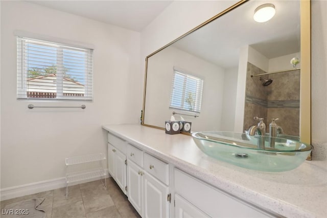 bathroom with baseboards, a tile shower, tile patterned flooring, and vanity