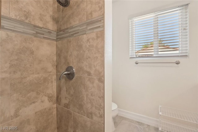 bathroom with baseboards, toilet, and tiled shower