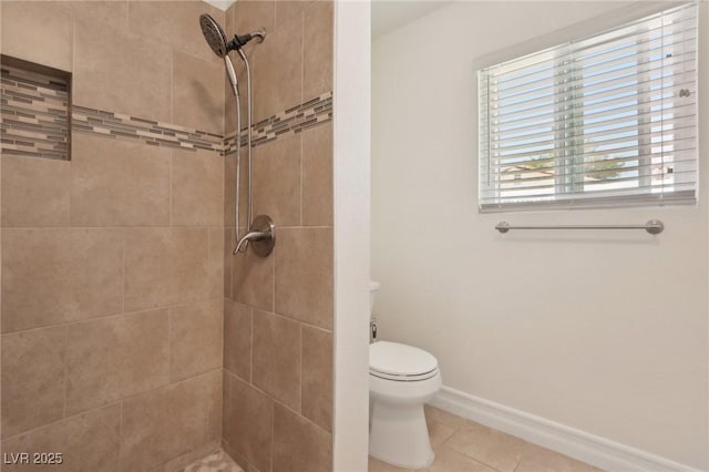 bathroom featuring tile patterned floors, a tile shower, and toilet