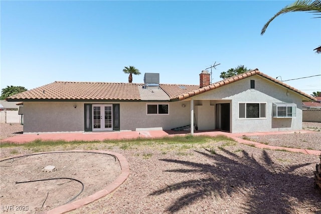 back of house with a patio area, stucco siding, french doors, and a chimney