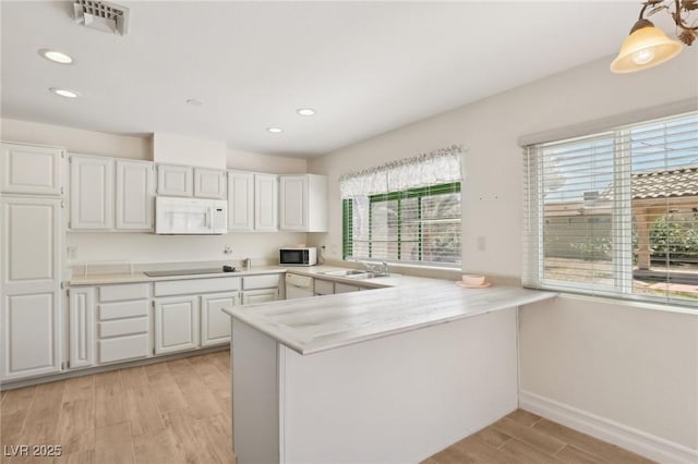 kitchen with light wood-type flooring, white cabinetry, a peninsula, and white appliances