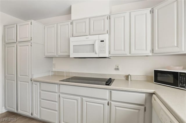 kitchen with light countertops, wood finished floors, white cabinets, and white appliances