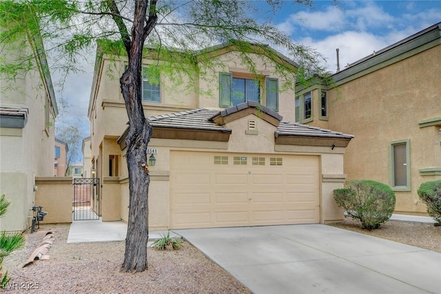 view of front of property featuring an attached garage, stucco siding, a gate, concrete driveway, and a tiled roof