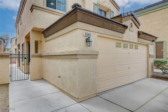 garage with a gate, fence, and concrete driveway