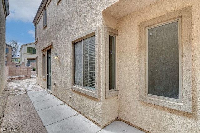 view of property exterior featuring a patio, stucco siding, and fence