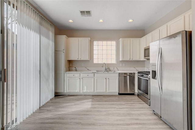 kitchen with a sink, white cabinets, stainless steel appliances, and visible vents