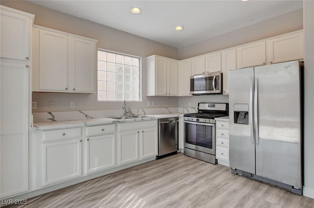 kitchen with a sink, light wood-style floors, stainless steel appliances, recessed lighting, and white cabinetry