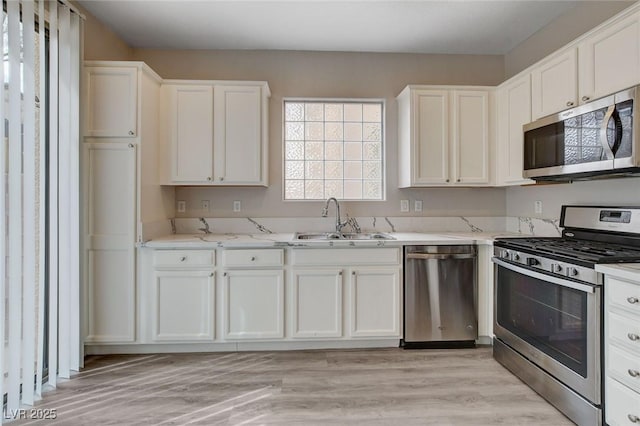 kitchen with white cabinets, appliances with stainless steel finishes, a healthy amount of sunlight, and a sink