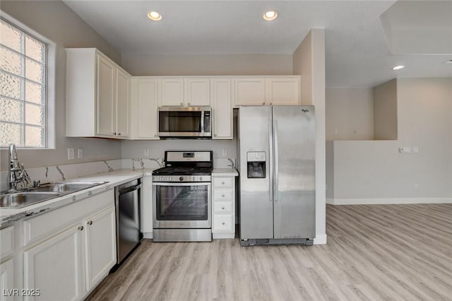 kitchen featuring recessed lighting, white cabinets, a sink, light wood-style flooring, and stainless steel appliances