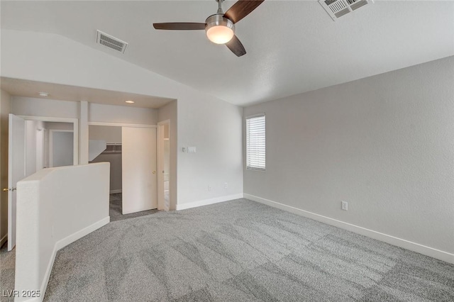 empty room featuring ceiling fan, vaulted ceiling, carpet flooring, and visible vents
