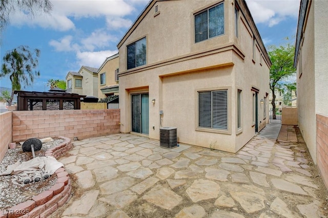 rear view of property with a patio, central AC, a fenced backyard, and stucco siding