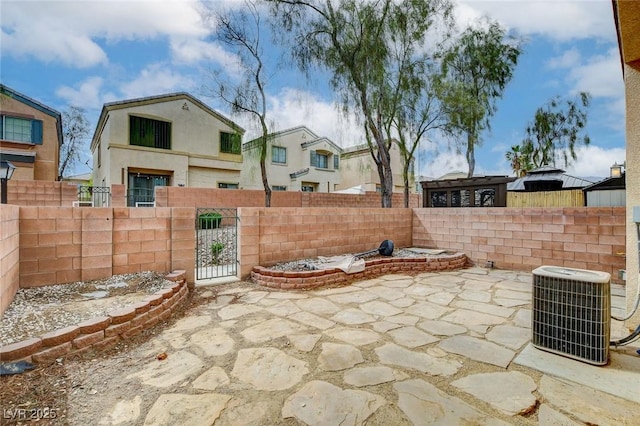 view of patio / terrace featuring a gate, a residential view, central AC unit, and a fenced backyard