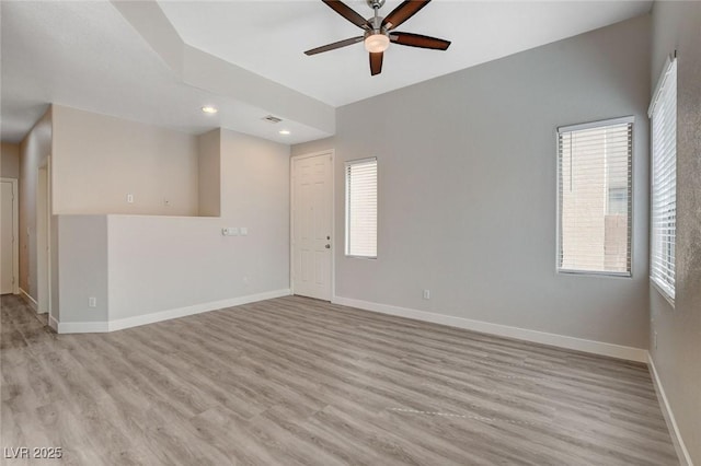 spare room with a ceiling fan, baseboards, a wealth of natural light, and light wood finished floors