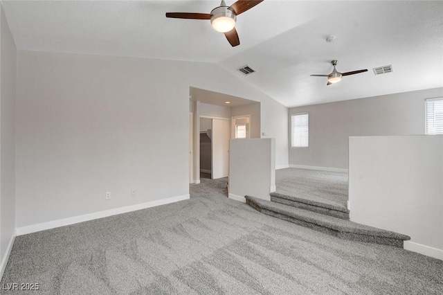 carpeted spare room featuring a ceiling fan, a wealth of natural light, and lofted ceiling