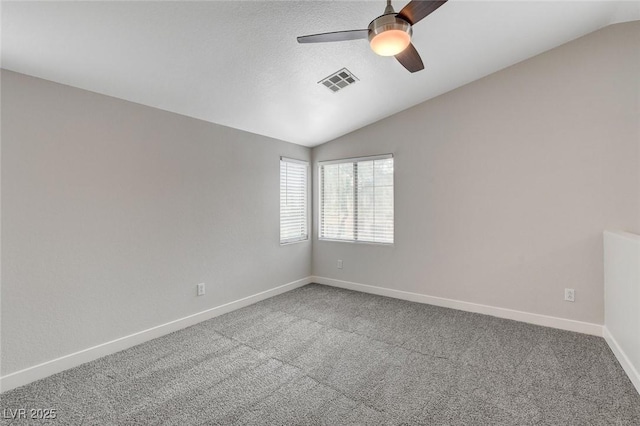 empty room with carpet flooring, ceiling fan, vaulted ceiling, and visible vents