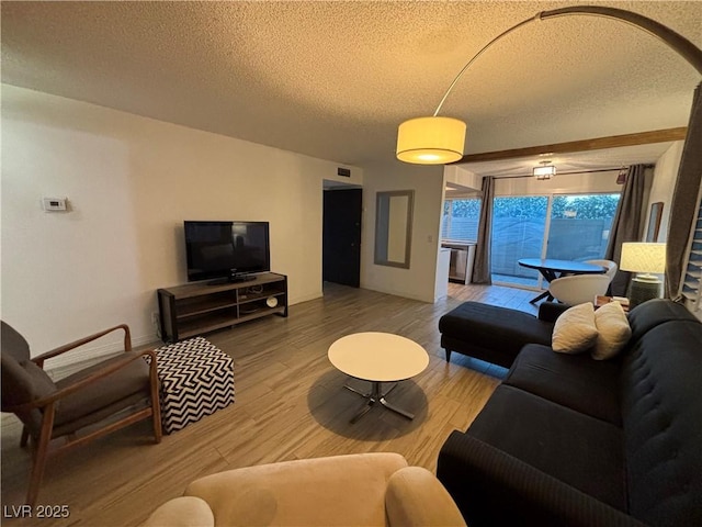 living room featuring visible vents, a textured ceiling, and wood finished floors