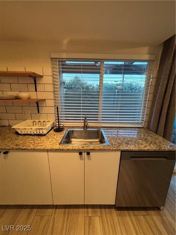 interior space featuring open shelves, a sink, light wood-style floors, tasteful backsplash, and stainless steel dishwasher