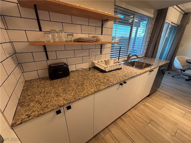 kitchen with open shelves, decorative backsplash, light wood-style floors, white cabinets, and a sink