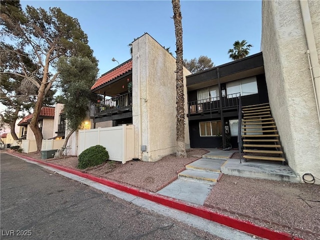 view of building exterior with fence and stairway