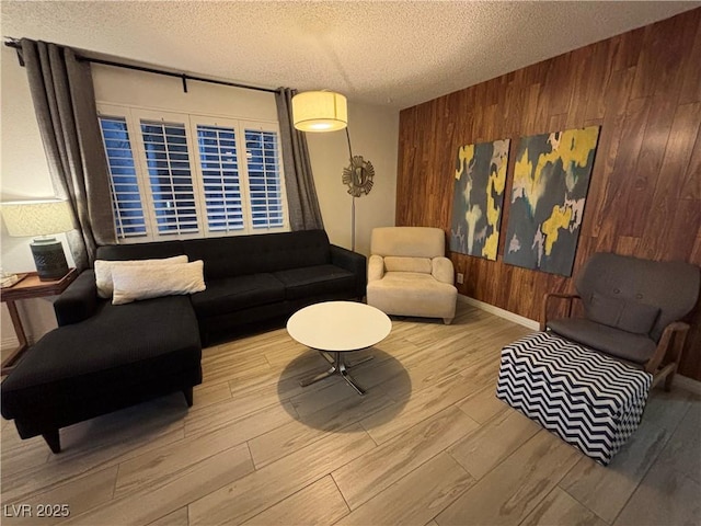 living area featuring baseboards, a textured ceiling, wood finished floors, and wooden walls